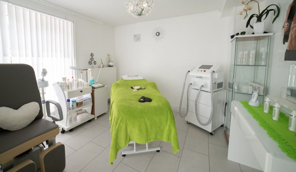 Bright and cozy clinic room featuring a comfortable treatment bed and modern equipment.